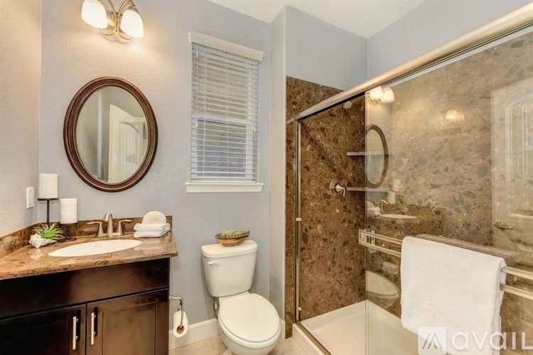 A bathroom with a toilet, sink, mirror, and shower.