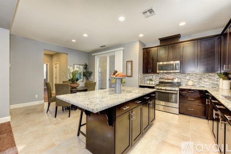 A modern kitchen with dark brown cabinets and a white island.