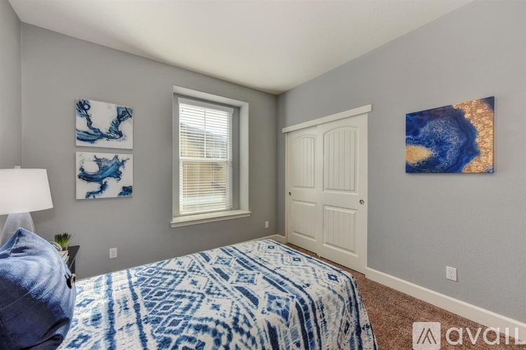 A bedroom with a bed, a window, and two pieces of artwork on the wall.