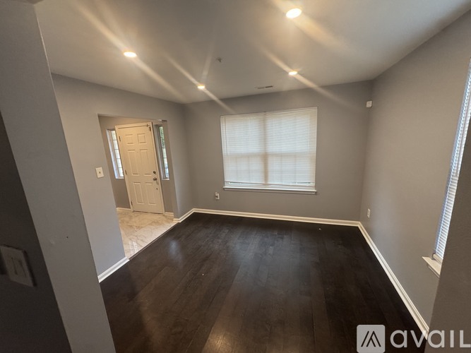 A room with wooden floors and a window with blinds.