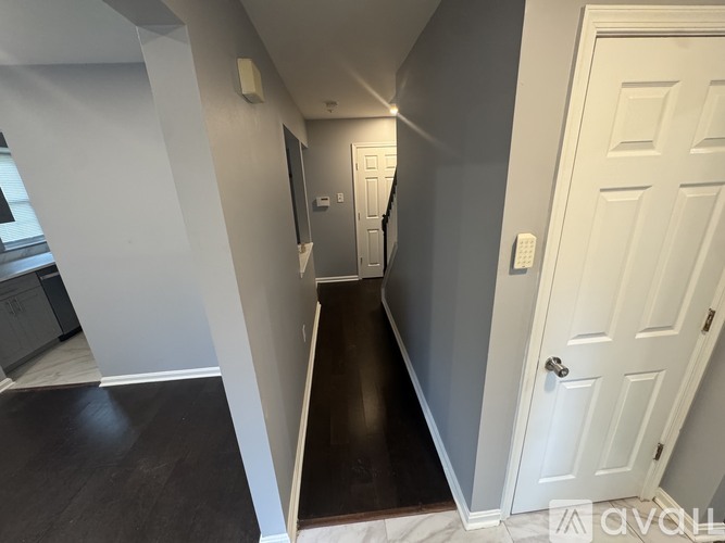 A hallway with a white door and a white wall.