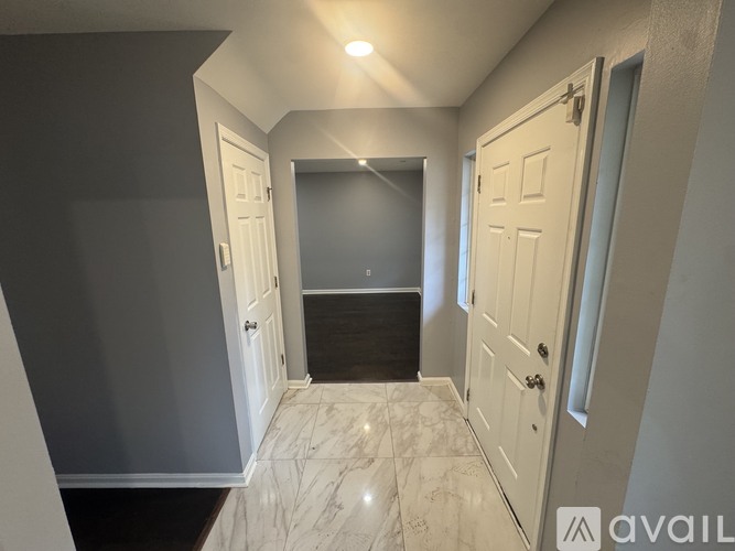 A hallway with marble flooring and white doors.
