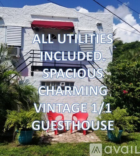 A white building with a red awning and a sign that reads "ALL UTILITIES INCLUDED. SPACIOUS CHARMING VINTAGE 1/1 GUESTHOUSE".