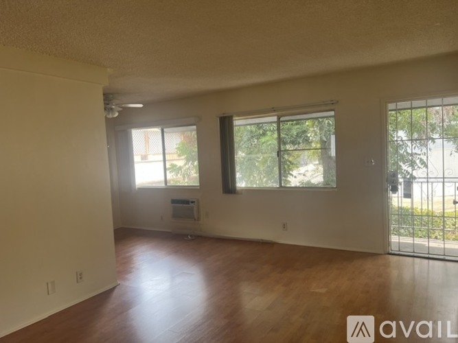 Empty room with wooden floors and two windows.