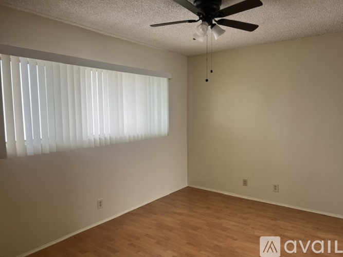 A room with a ceiling fan and wooden flooring.