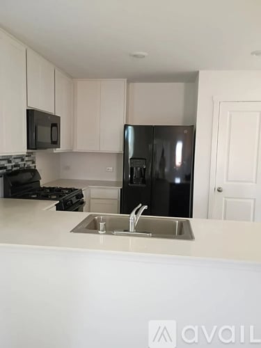 A kitchen with a black fridge and a white counter.