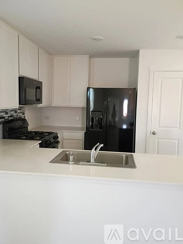 A kitchen with a black fridge and a white counter.