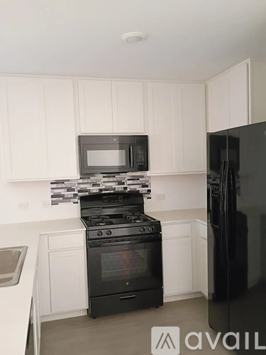 A kitchen with black appliances and white cabinets.