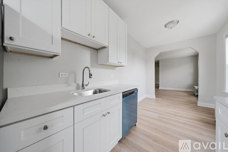 A kitchen with white cabinets and a wooden floor.