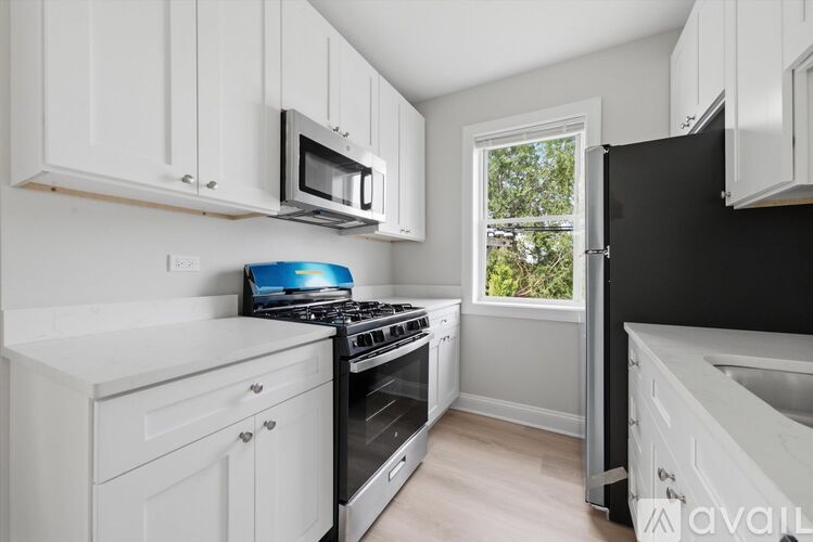 A kitchen with white cabinets and a black refrigerator.