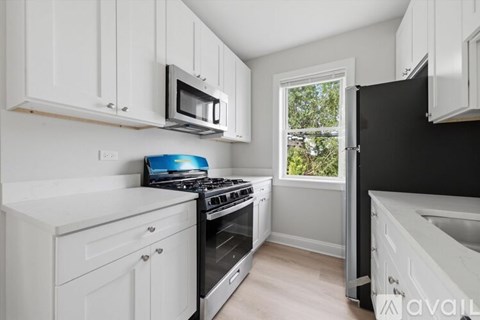 A kitchen with white cabinets and a black refrigerator.