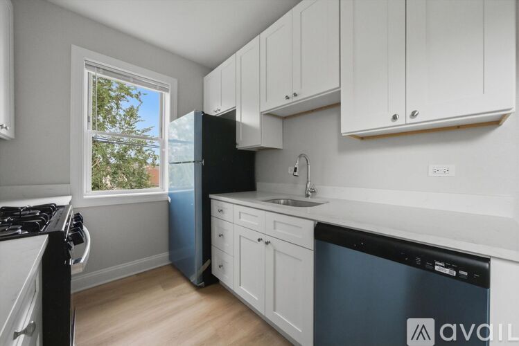 A kitchen with white cabinets and a black dishwasher.