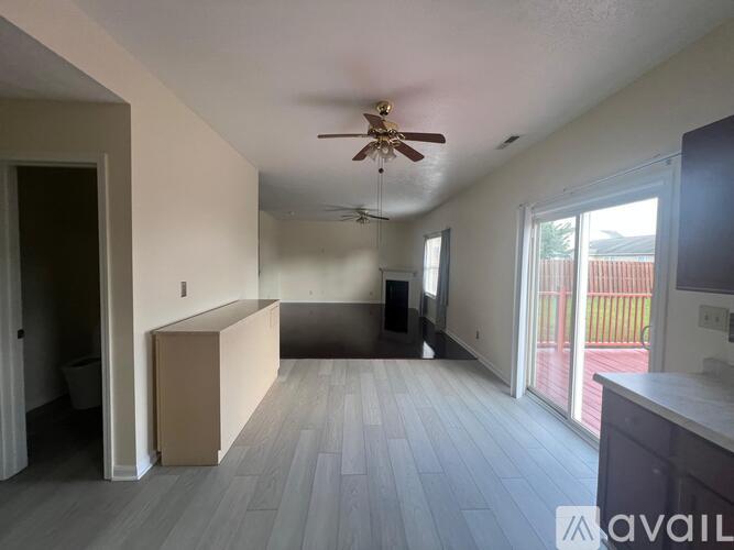 A living room with a ceiling fan and sliding glass doors.