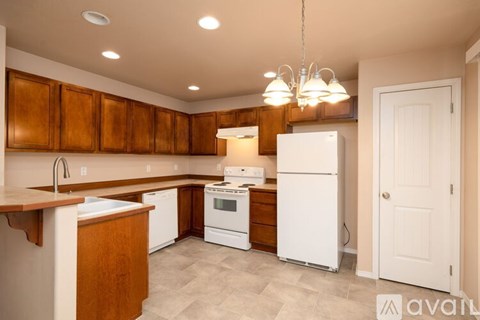 A kitchen with white appliances and wooden cabinets.