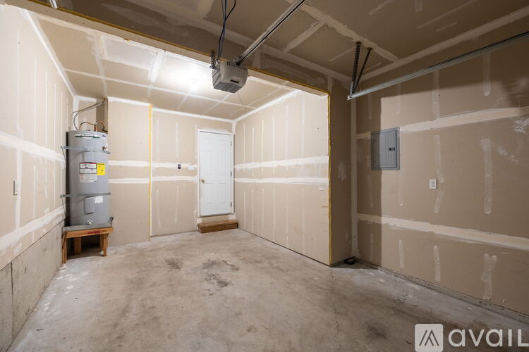 A spacious, unfinished room with a water heater and electrical panel.