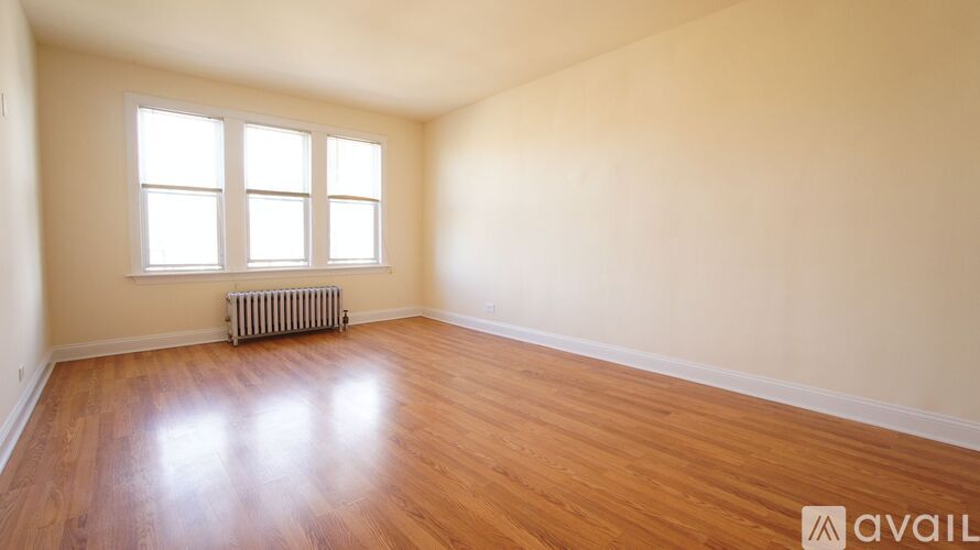 A room with wooden floors and a window with a radiator beneath it.
