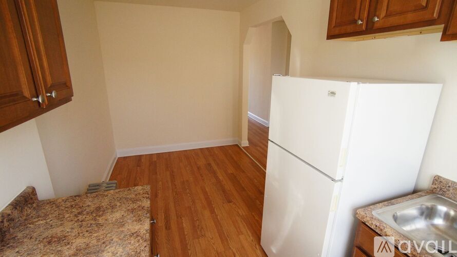A kitchen with a white fridge, wooden cabinets, and a granite countertop.