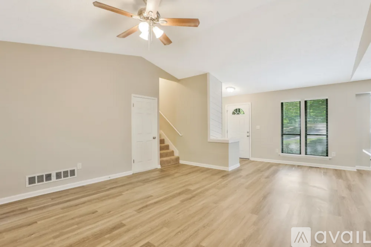 A spacious room with wooden flooring and a ceiling fan.