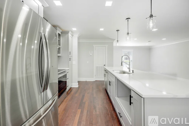 A modern kitchen with a stainless steel refrigerator and wooden flooring.