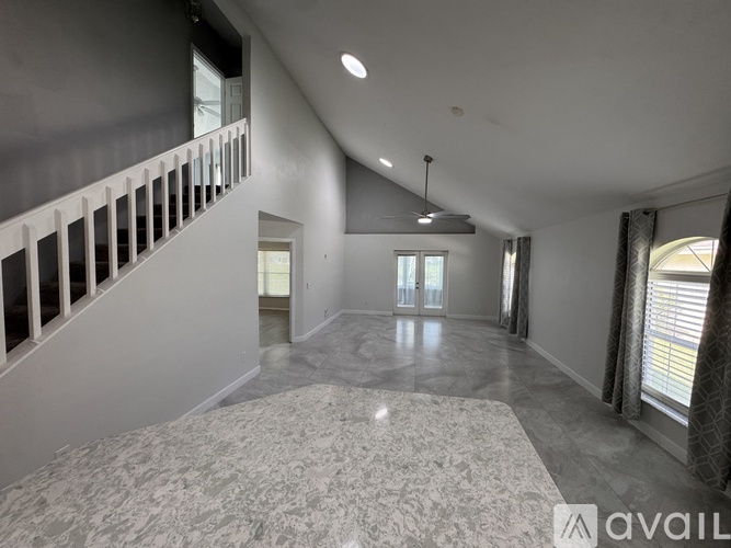 A spacious room with a carpeted floor and a staircase with white railings.