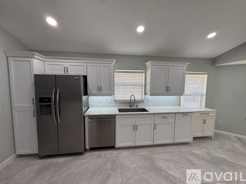 A kitchen with white cabinets and a stainless steel refrigerator.
