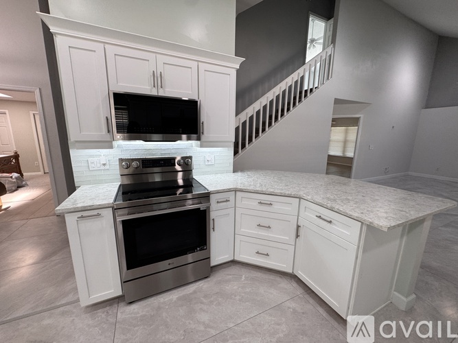 A modern kitchen with white cabinets and a marble countertop.