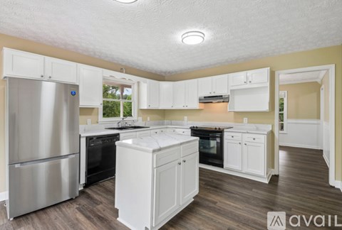 A kitchen with white cabinets and a stainless steel refrigerator.