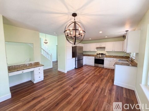 A large open kitchen and living room with wood flooring and a chandelier.