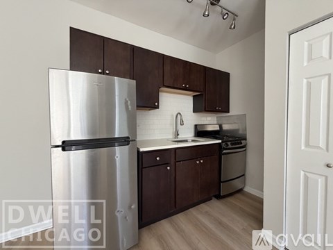 A kitchen with a refrigerator, stove, and cabinets.