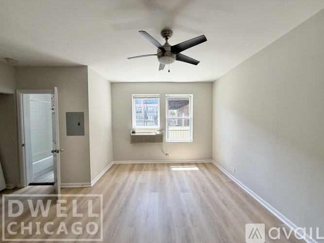 A room with a ceiling fan and a window with blinds.