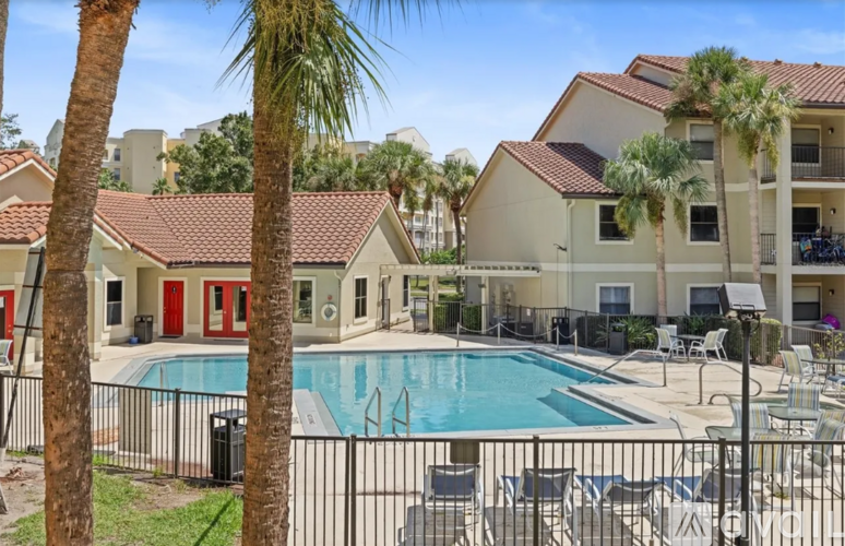 A pool surrounded by chairs and palm trees.