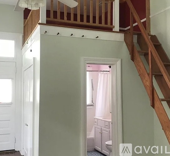 A white bathroom with a wooden staircase leading to the upper floor.