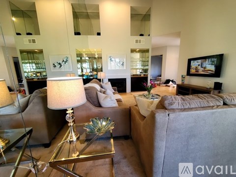 A living room with a glass coffee table and a lamp on it.