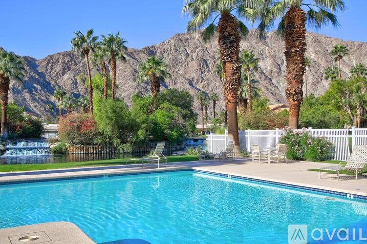 A pool surrounded by palm trees and mountains.