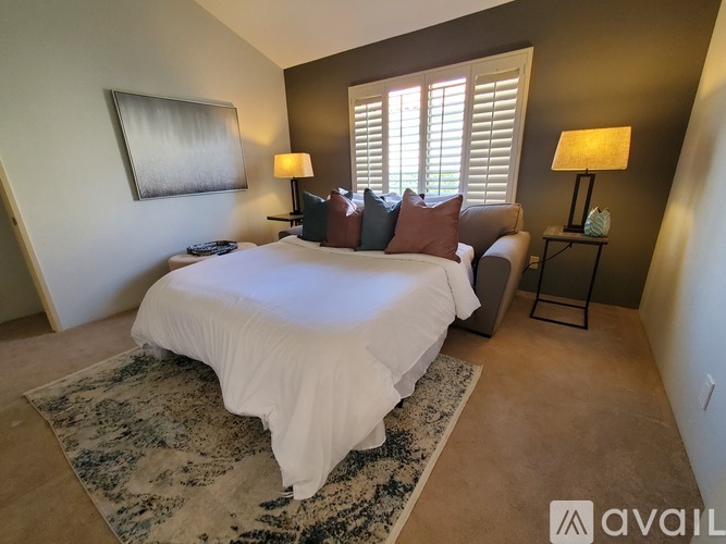 A bedroom with a large bed and a rug on the floor.