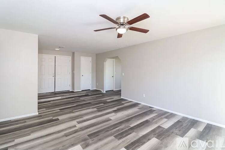 A room with a ceiling fan and wood flooring.