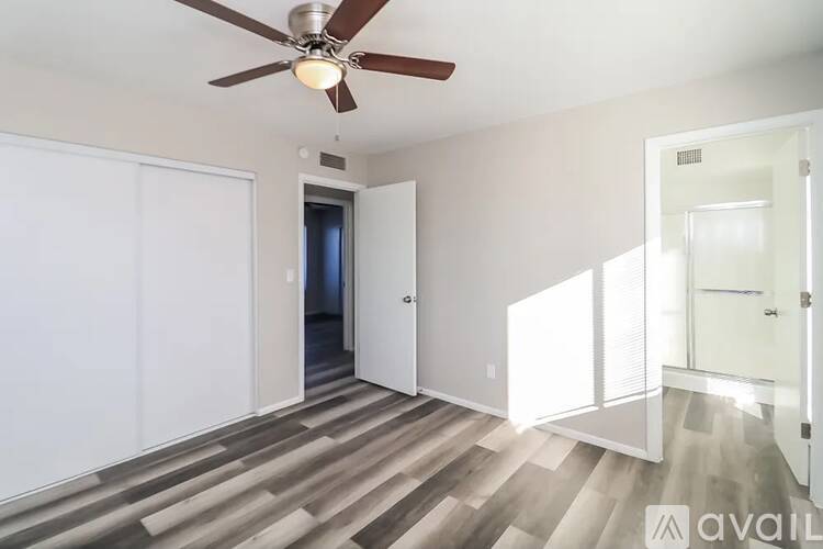 A room with a ceiling fan and wooden flooring.