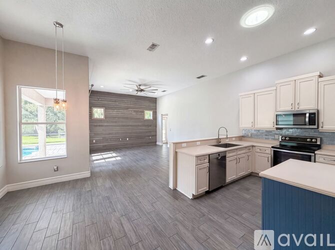 A spacious kitchen with wooden flooring and a ceiling fan.