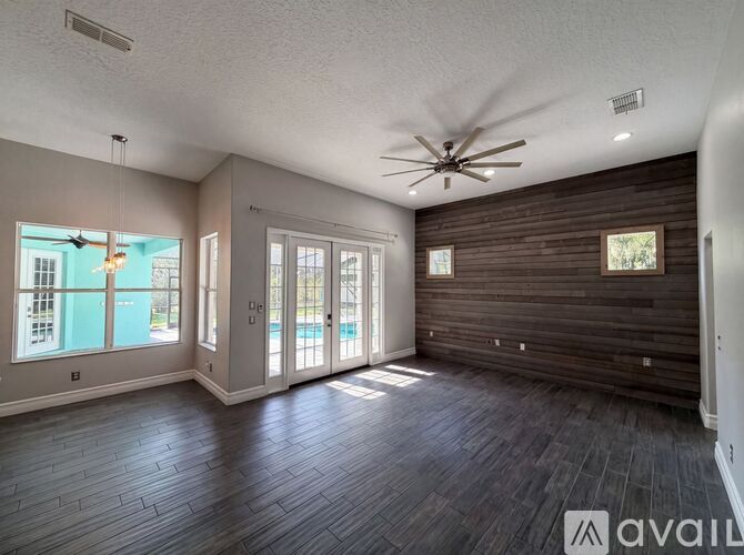 A spacious room with a ceiling fan and sliding glass doors.