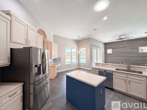 A kitchen with a black refrigerator and a blue island.