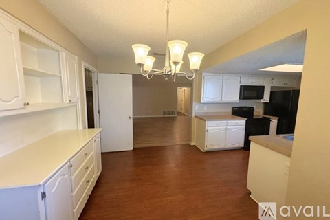 A kitchen with white cabinets and a wooden floor.