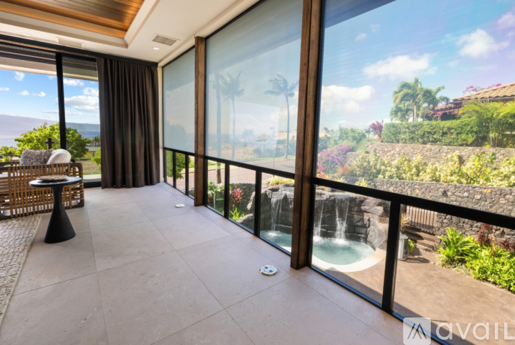 A balcony with a table and chairs overlooking a pool and a waterfall.