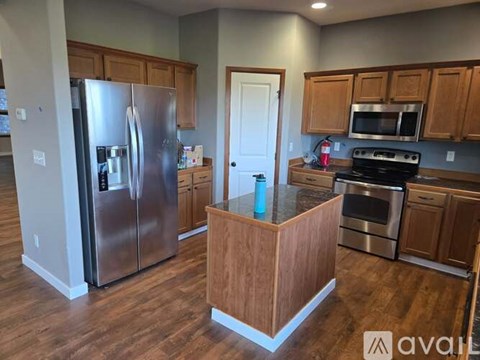 A kitchen with wooden cabinets and a stainless steel refrigerator.