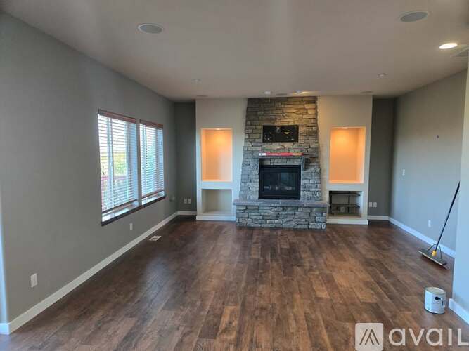A spacious living room with a stone fireplace and wood flooring.