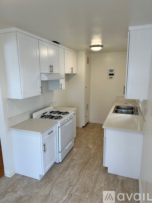 A kitchen with white cabinets and a stove top oven.