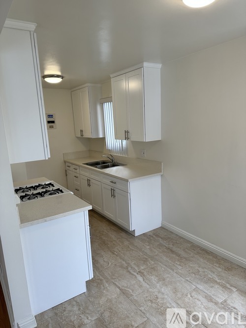 A kitchen with white cabinets and a tiled floor.