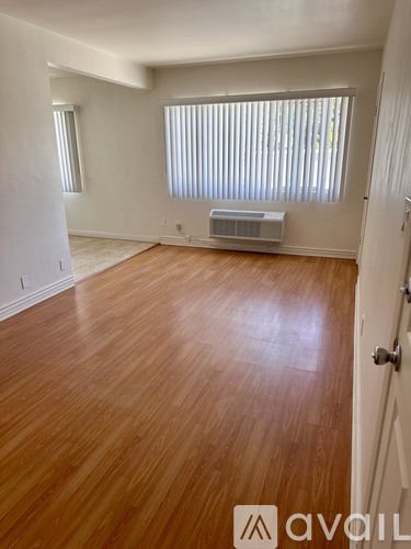 A room with wooden floors and a window with blinds.
