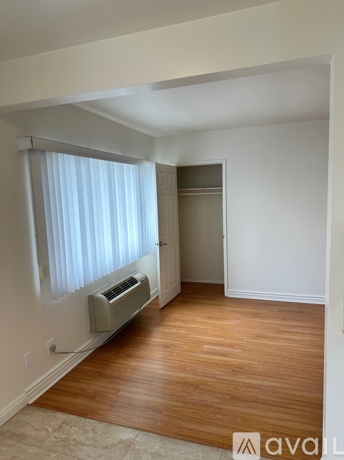 A room with a window covered by white curtains and a wall-mounted air conditioner.