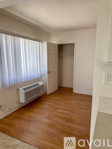 A room with a window covered by white blinds and a wall-mounted air conditioner unit.