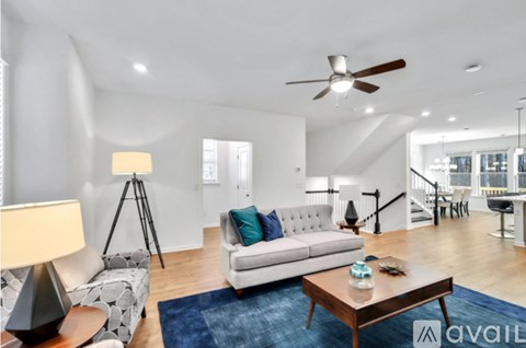A living room with a white couch and a blue rug.